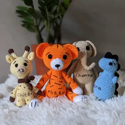 A custom set of animal friends, including a giraffe, tiger, elephant, and dinosaur, each personalized with an embroidered name.