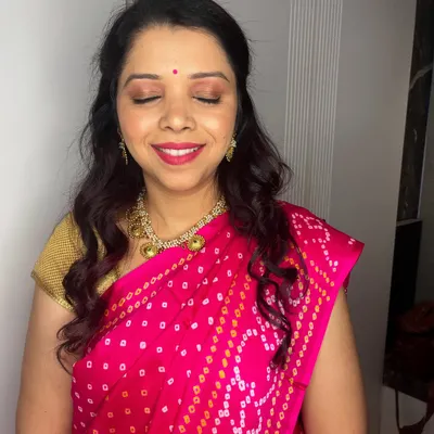 A close-up of Anita's festive makeup. The look is natural and radiant, with a focus on glowing skin, a touch of shimmer on the eyes, and a pretty red lip.