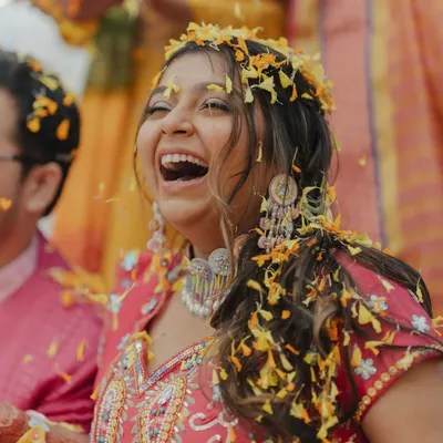 A bride's infectious laughter during her Haldi ceremony as she's showered with flower petals. This is the kind of pure, unscripted joy we love to capture.