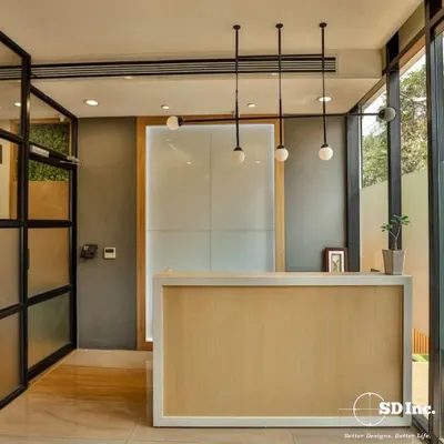 This reception area design combines a simple wooden desk with elegant globe lighting and glass walls. The result is a bright, airy, and professional space that immediately puts visitors at ease.
