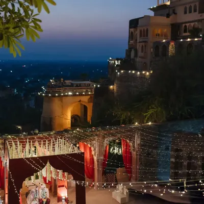 A magical wedding ceremony at dusk, with the historic Neemrana Fort-Palace illuminated against the twilight sky, creating a truly royal and unforgettable ambiance.