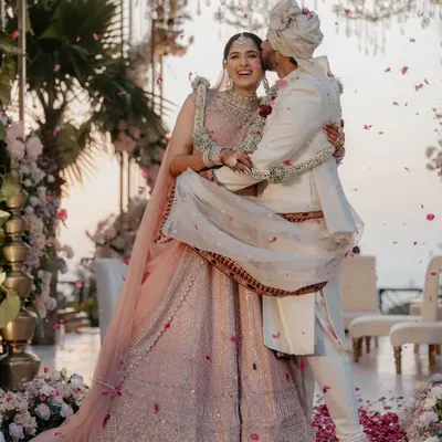 A moment of pure joy. This bride's pastel pink lehenga is paired with soft pink makeup tones and a clean bridal bun, creating a fresh and modern Phera look.