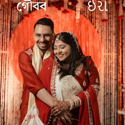 A classic portrait of a Bengali bride and groom, their names beautifully written in Bengali script. They are wrapped in a loving embrace against a backdrop of crimson and gold, a timeless frame from their special day.