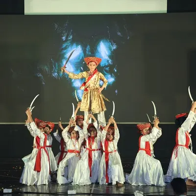 This is a powerful moment from our "Tanaji" act, a historical tribute performance. The lead performer is lifted by the group, holding swords to create a dramatic and heroic pose.