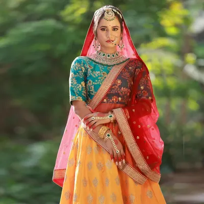 This Heeramandi-inspired look is a great example of a full thematic collaboration. The rich colors of the yellow, red, and teal lehenga stand out beautifully against the lush green outdoor background, creating a regal portrait.