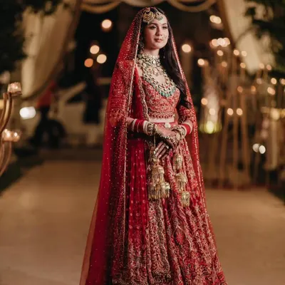 A breathtaking full-length shot of the bride in a classic red Tarun Tahiliani lehenga. The intricate embroidery and timeless silhouette make this a truly iconic bridal look.