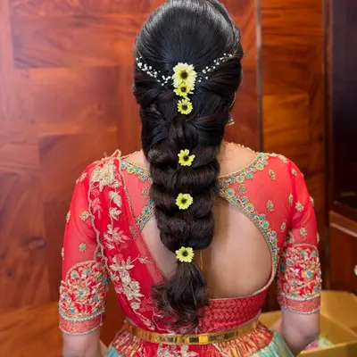 A classic South Indian bubble braid, neatly sectioned and adorned with fresh yellow flowers and a delicate hair accessory. This style is both traditional and chic.
