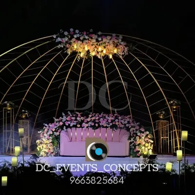 A breathtaking outdoor reception setup featuring a large, domed metal structure, soft floral arrangements, and dramatic uplighting to create an enchanting evening ambiance.