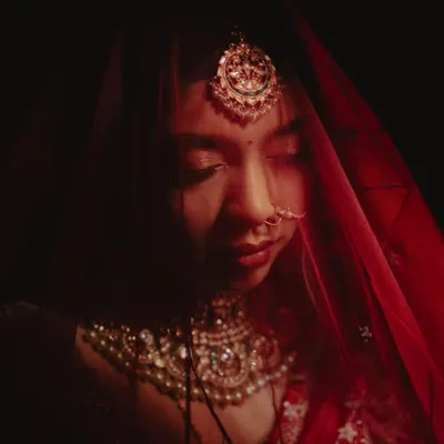 A moment of quiet reflection for the bride. We used dramatic, low-key lighting to create this artistic and soulful portrait, highlighting the intricate details of her jewelry and the emotion on her face.