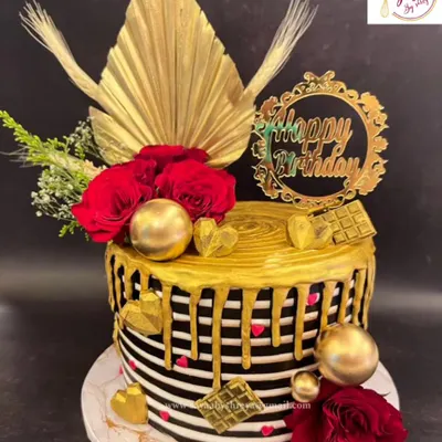 This black and white striped cake with a dramatic gold drip is a statement of modern elegance. Adorned with red roses, gold hearts, and dried palm spears, it's a luxurious centerpiece for a sophisticated birthday.