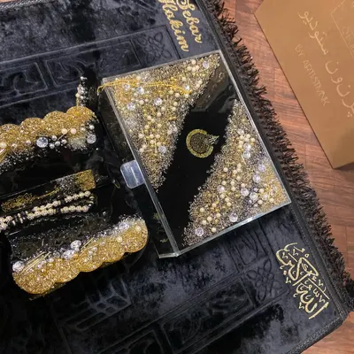 My luxurious black and gold gift set. This set includes a personalized Quran box, a matching Quran holder (rehal), and a crystal tasbih, all laid out on a black velvet prayer mat with the client's name embroidered.
