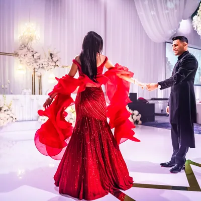 A candid moment from a client's reception. The bride is wearing a stunning red Gaurav Gupta gown with signature ruffled sleeves, creating beautiful movement on the dance floor. It was the perfect choice for her vibrant personality.
