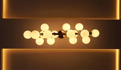 A modern, sculptural chandelier with globe lights, set within a cove-lit ceiling. This type of lighting serves as both a functional fixture and a piece of art.