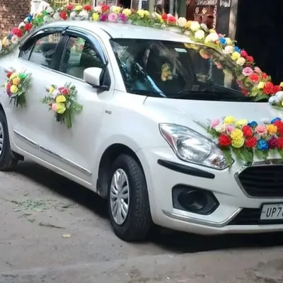 A wedding car decorated with bouquets of colorful artificial flowers on the hood, roof, and doors.