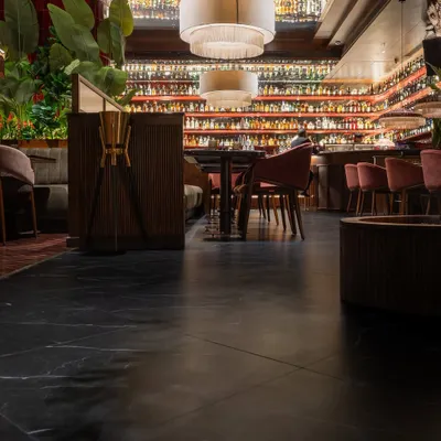 The flooring is the foundation of this restaurant's atmosphere. For Hikki, I selected a large-format black marble-style tile with subtle white veining. This choice provides a sleek, sophisticated base that grounds the vibrant red wall tiles and warm wood furnishings, creating a balanced and moody ambiance.