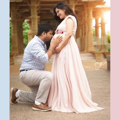 A tender kiss for the baby on the way. This outdoor couple's portrait captures the love and anticipation that fills this special time, set against a beautiful architectural backdrop.