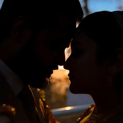 A powerful close-up silhouette of the couple, their faces close together, with the last light of the sun creating a fiery rim light around them.