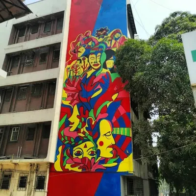Titled "The Genesis," this massive, colorful abstract mural in Marol celebrates womanhood and nature. The vibrant blues, reds, and yellows represent the energy and power of women coming together.