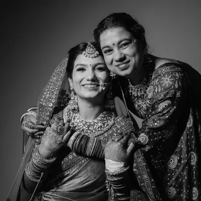 A heartwarming black and white portrait of the bride sharing a beautiful, smiling moment with her mother. This candid shot captures the precious bond and emotion of the wedding day.