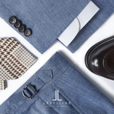A flat lay showcasing the key elements of a bespoke outfit: herringbone fabric, side adjusters on the trousers, classic buttons, and a complementary pocket square.
