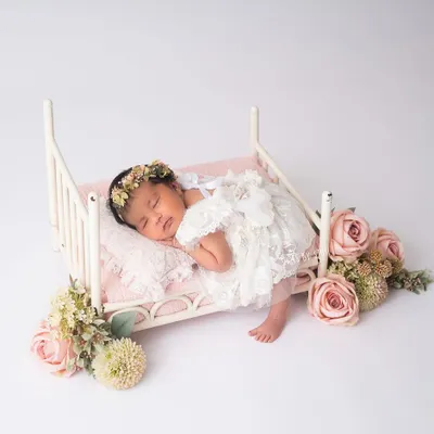 A perfect little angel asleep on a tiny bed, surrounded by flowers. This is a classic newborn setup that I love to create. The delicate lace outfit and floral details make it a truly timeless portrait.
