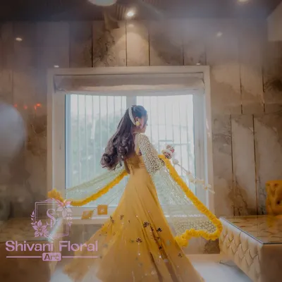 A beautiful bride twirling in her Haldi outfit, adorned with a full set of my floral creations. The look includes a stunning jasmine bud dupatta with a marigold border, heavy kalire, and matching floral handcuffs.