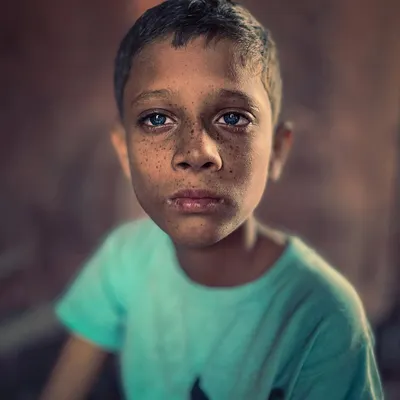 A striking close-up portrait of a child with freckles and intense blue eyes, his direct and soulful gaze creating a powerful connection.
