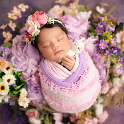 This baby girl is sleeping so peacefully, surrounded by a bed of lavender and pink flowers. I carefully arrange each floral element to create a lush, garden-like feel for the portrait.