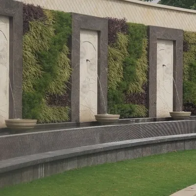 This large-scale exterior wall combines the soothing element of water with the natural beauty of vertical gardens. We designed this installation with repeating sections of living walls and elegant water fountains, creating a grand and serene feature for a commercial property.