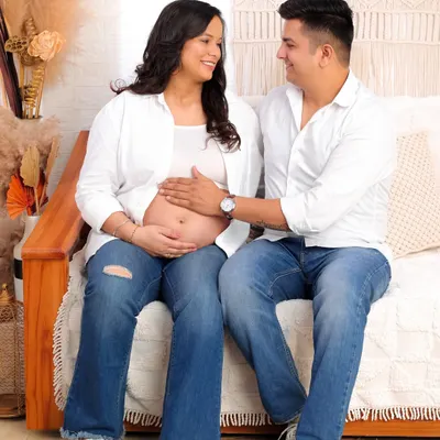 A serene and intimate portrait of expecting parents in our cozy studio setting. The focus is on their connection and the gentle touch on the baby bump, capturing the quiet excitement before the baby's arrival.