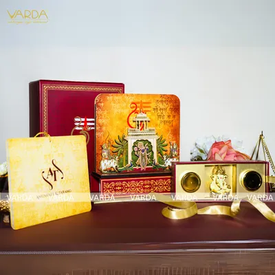 This invitation suite is themed around Shreenathji, featuring temple-style artwork on the box and cards. The set includes a 3D devotional box, a gift bag, and a smaller hamper with a Ganesha idol, creating a complete spiritual gifting experience.