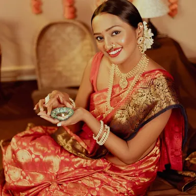 Aali Diwali Aali! Capturing the beautiful, warm glow of Diwali with a model holding a diya. The traditional red saree and festive decor create a perfect celebratory mood.