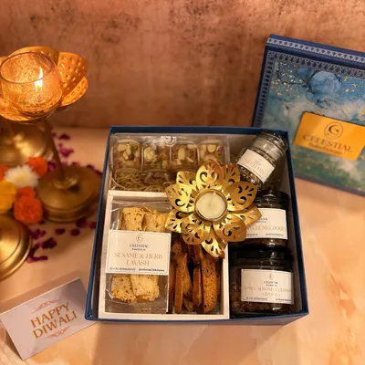 A glimpse into our festive Diwali collection. This gift box features our sesame and herb lavash, assorted healthy sweets, and a decorative diya, all presented in an elegant blue box.