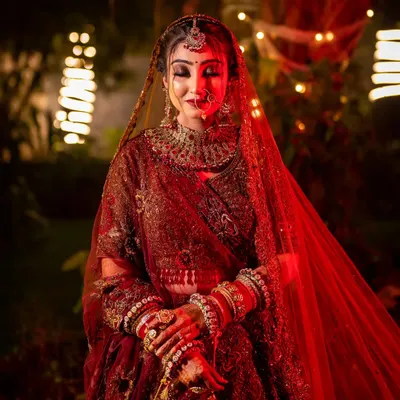 A breathtaking bridal portrait with dramatic red lighting and a soft focus, highlighting the bride's regal presence and intricate jewelry.