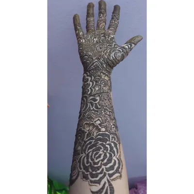 This is a full-arm design with fresh henna paste, showing the right hand. The pattern is dense with large rose motifs and traditional Indian filler patterns.