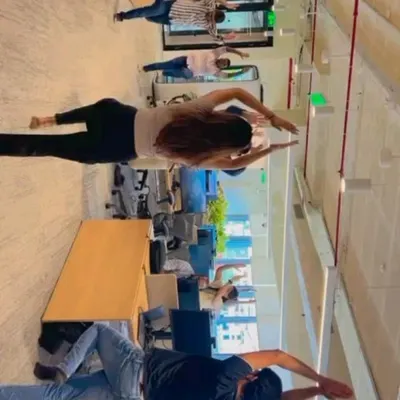Employees participating in a standing side stretch during a corporate yoga session. This simple movement helps to lengthen the spine and release tension in the shoulders and sides, all while standing right in the office space.