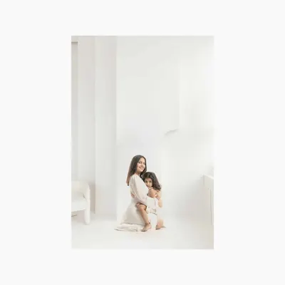 A hug that says everything. This simple, heartfelt portrait of a mother embracing her daughter in a clean, white studio setting is a testament to the eternal and unconditional love they share.
