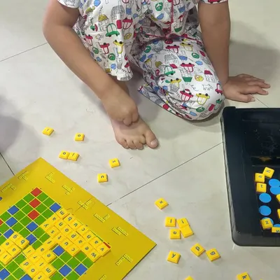 We make learning words a game, not a chore. Using a simple Scrabble board, we practice spelling and reading three and four letter words. It’s a playful way to build vocabulary and early literacy skills right on the living room floor.