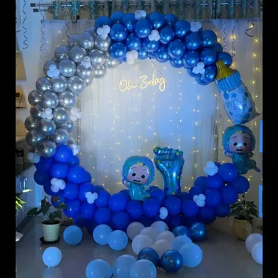 This is a complete 'Oh Baby' themed setup I created for a baby shower in Bangalore. It features a circular backdrop with a blue and silver balloon arch, a custom 'Oh Baby' neon sign, Cocomelon character foil balloons, and a curtain of fairy lights for a magical effect.