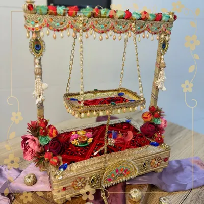 Celebrate the divine swing of Lord Krishna with our custom-made Janmashtami jhula. This piece is handcrafted with a beautiful red base, floral decorations, and pearl details, creating a perfect seat for Ladoo Gopal.