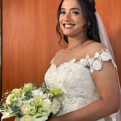 A vision in white. This bride is the picture of happiness, holding her bouquet with a radiant smile. Her makeup is soft and luminous, designed to look fresh and beautiful all day long.
