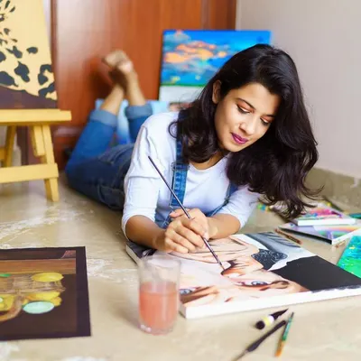 This is me, completely absorbed in my work. I often paint on the floor, surrounded by my canvases and tools. It's my personal space to create and just be.