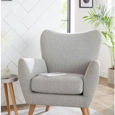 A completely customized armchair with a classic mid-century modern design. The light grey fabric and wooden legs make it a versatile piece for any living room.