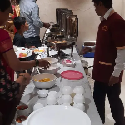 A member of my team, in his Mariya Caterers uniform, assisting guests at the buffet line. We are always present to ensure the food containers are full and to help guests with service.