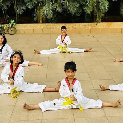 The foundation of powerful kicks is flexibility. Here, our young students work on their splits, building the flexibility needed for high-level techniques.