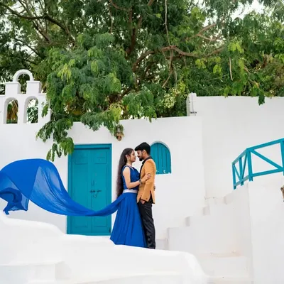 A picture-perfect moment with a Santorini vibe. The bride's flowing blue gown creates a stunning wave of color against the white architecture and blue doors.