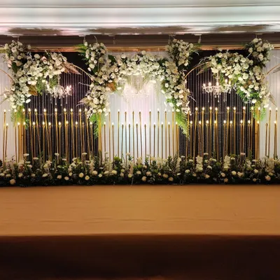 A full view of our candle wall stage design, where hundreds of lights create a warm, mesmerizing glow. This setup, framed by arches of white flowers, is perfect for a grand wedding reception or an elegant awards night.