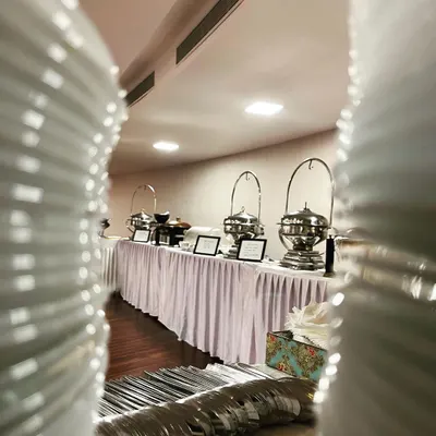 A view of our extensive buffet line, ready for service. This perspective through the stacked plates shows our readiness and attention to detail before guests arrive.