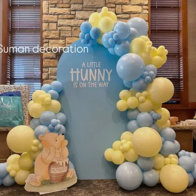 A sweet Winnie the Pooh themed baby shower. The backdrop reads "A Little Hunny is on the way" and is framed by a beautiful balloon garland in pastel yellow and blue.