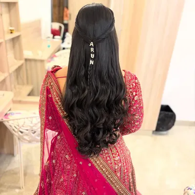 A modern half-up style with soft waves, personalized with a custom 'ARUN' hair accessory. I can add unique touches like this for your special day.